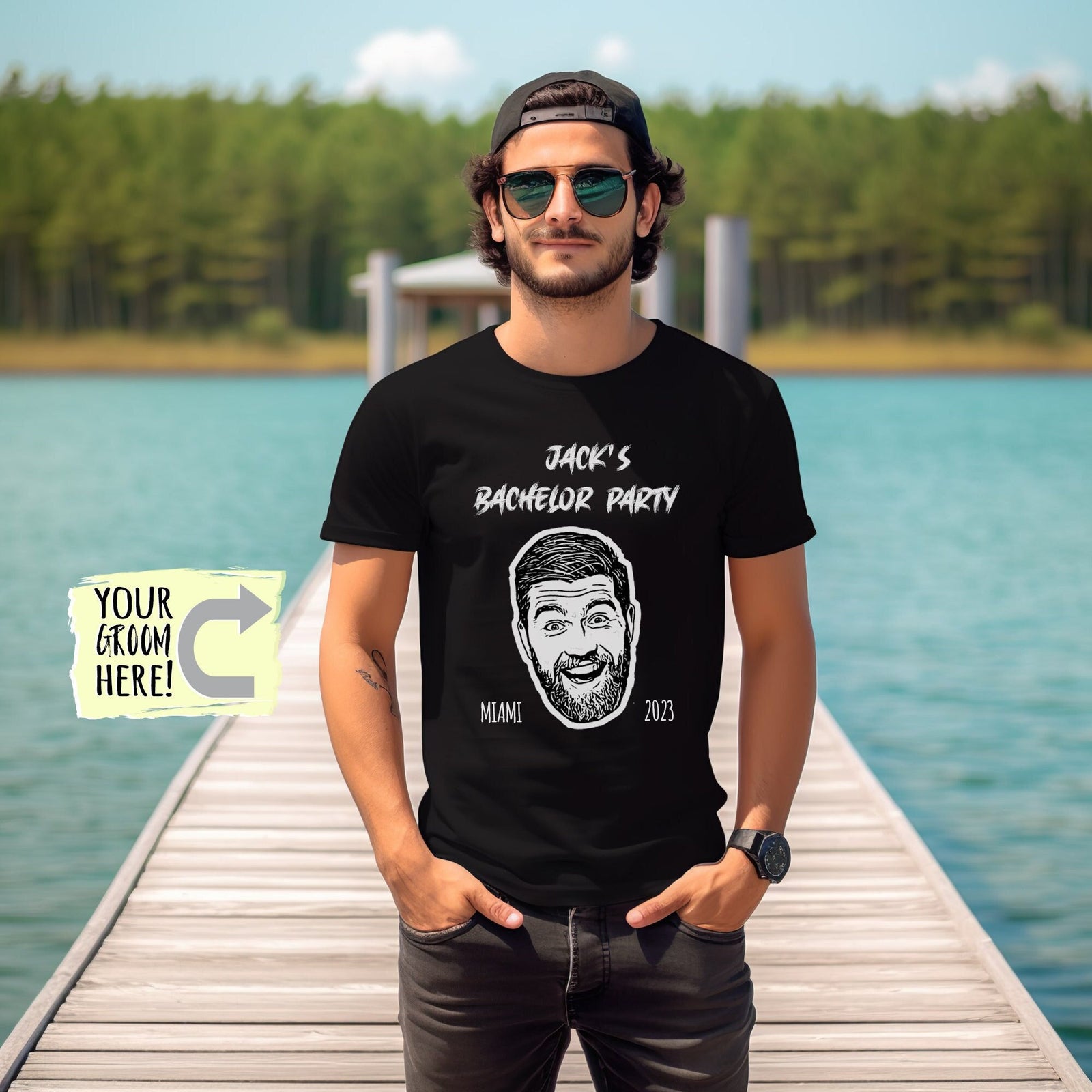 May include: A black t-shirt with white text that reads 'Jack's Bachelor Party' and a cartoon drawing of a man's face. The text 'Miami' and '2023' are below the drawing. The shirt is being worn by a person with a black cap and sunglasses.